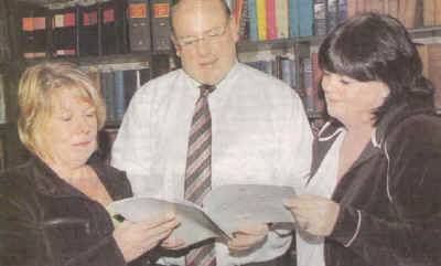 In this photograph from the Dundalk Democrat: Local solicitor James McGuill with the daughters of the victims of the Kay's Tavern bombing, Maura McKeever and Margaret English. They are seen here studying the just published Oireachtas committee report on the Dundalk bombing..